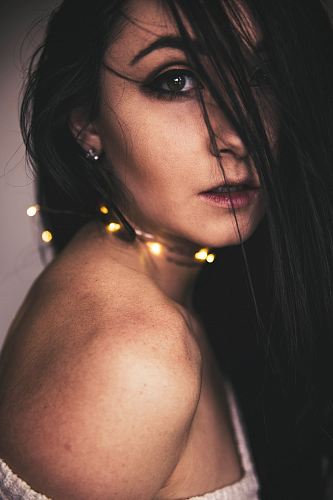 closeup photo of woman with string lights on neck