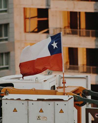 symbol selective focus photography of raised flag on white and yellow machine during daytime brown