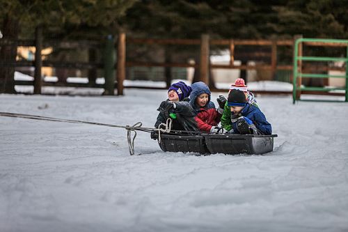 four children riding boat on snow