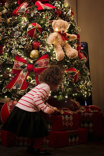 girl picking gift in front of pre-lit tree