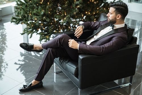 man sitting on black sofa chair while watching watch