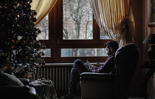 man sitting on sofa chair near Christmas tree