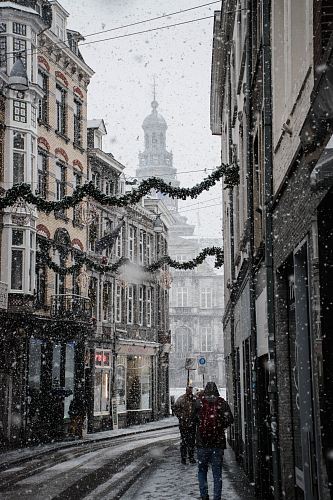 people walking near street between brown building during snow season