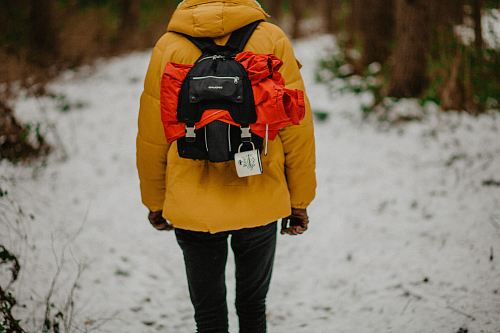 person carrying black backpack in road