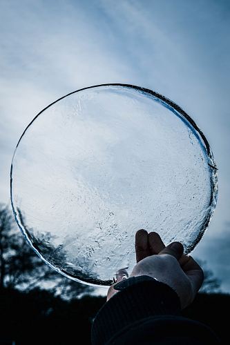 person holding round clear ice glass