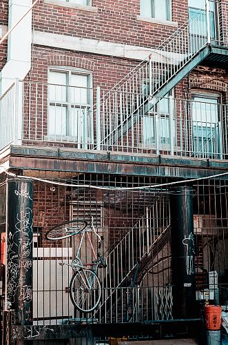 red and gray bicycle on metal railing on red concrete building at daytime