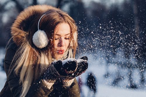 woman blowing snow on her hands