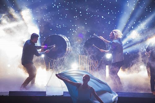 woman dancing in front of men playing drums on stage