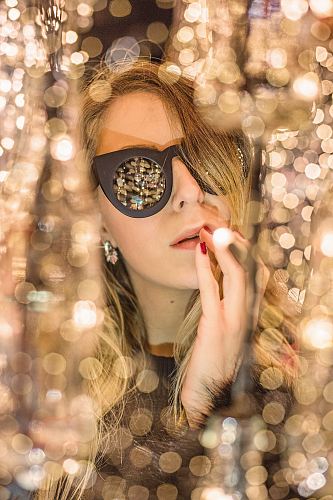 woman holding lips with black framed sunglasses