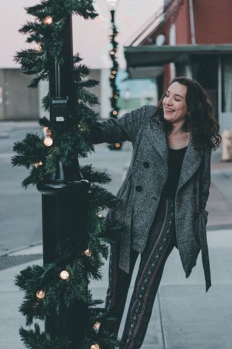 woman in gray coat holding post light