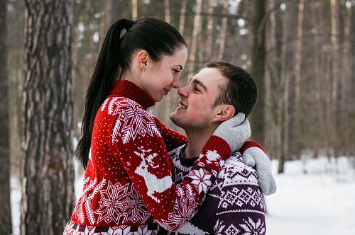 woman wearing red and white fair-isle knit sweater hugging man wearing brown and red fair-isle sweater