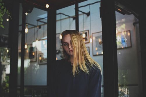 woman wearing white jacket leaning on glass wall