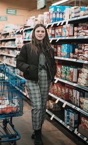 jacket woman standing near shopping cart and groceries inside warehouse coat