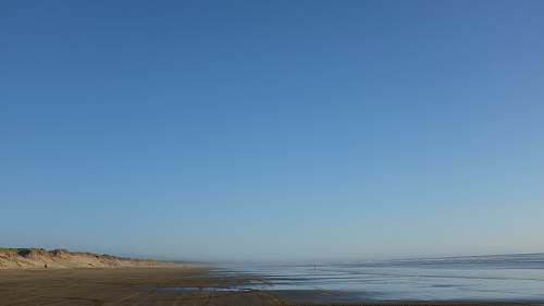 ocean body of water and gray seashore under blue sky blue