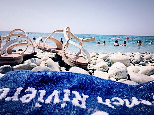 ocean pair of brown leather sandals on white stones nature