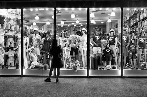human greyscale photography of woman standing outside store person