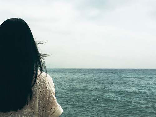 water woman facing body of water under cloudy sky woman