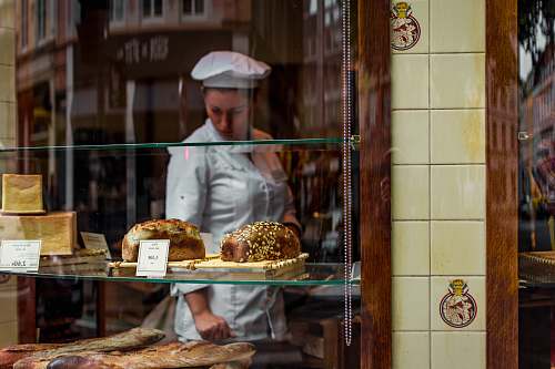 person baker inside glass covered store bakery