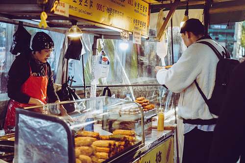 person man eating food in front of food ventor at night shop