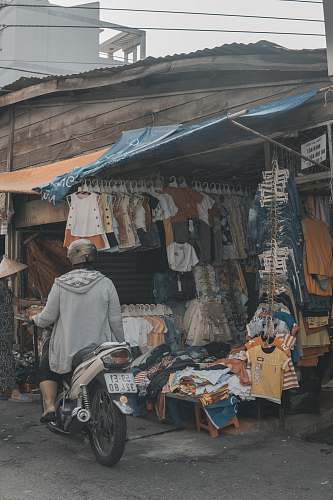 person person riding on motorcycle beside clothes display market