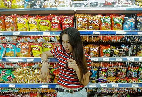 shop woman leaning on shelf while eating lollipop grocery store