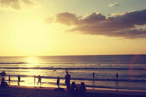 beach silhouette photography of people standing on shore near sea water