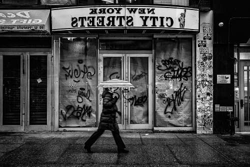 black-and-white person holding umbrella and walking on street graffiti
