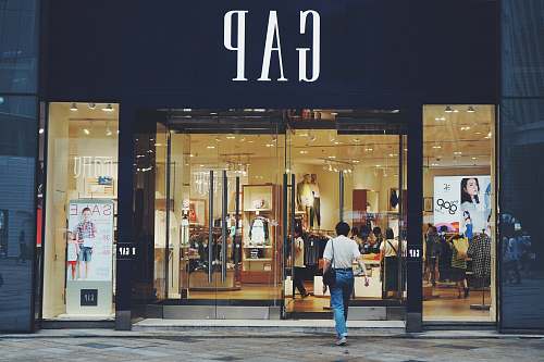 human person in white shirt and blue jeans walking inside GAP store footwear