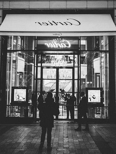 human person standing front of Cartier signage black-and-white