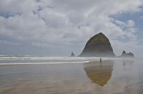 beach person standing on seashore with hill water