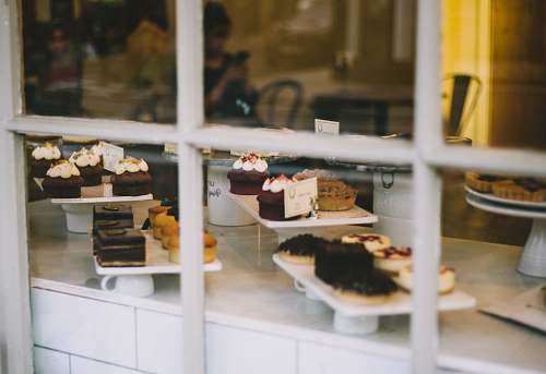 human assorted cakes near window bakery