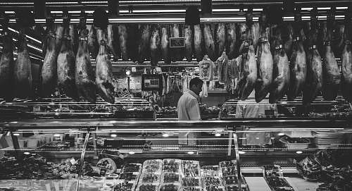black-and-white grayscale photography of man standing in store butcher shop
