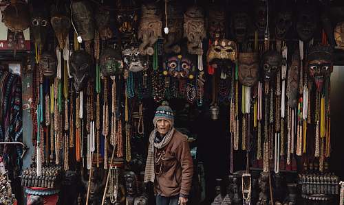 market man in brown jacket standing below hanging decors bazaar