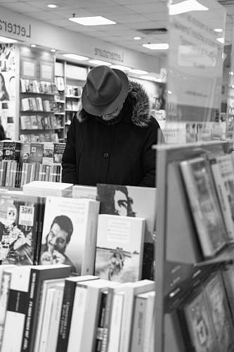 black-and-white man standing front of books hat