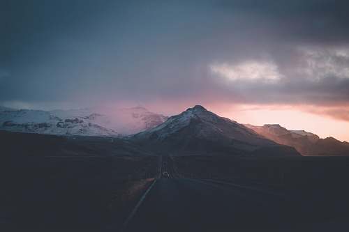 mountain car on road under grey sky mountain range