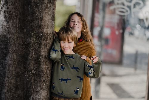 a little girl standing next to a tree