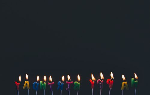 assorted-color Happy Birthday candles with flames