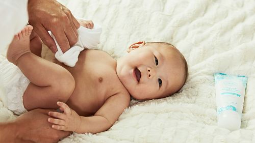 baby in diaper lying on bed
