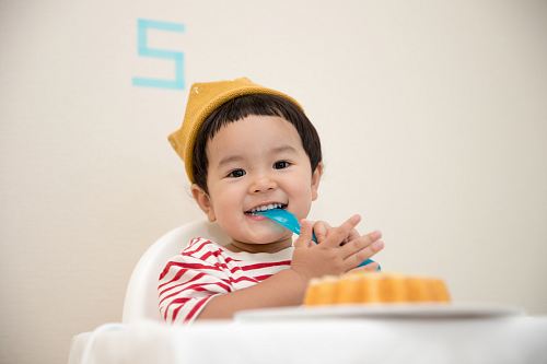 baby sitting on white chair while smiling at the camera