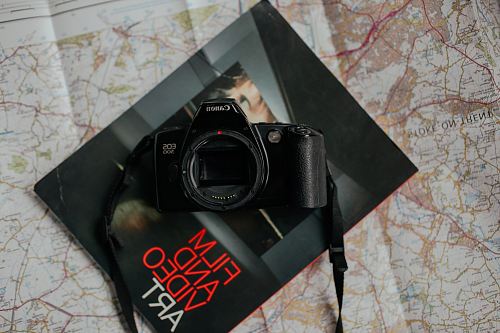 black Canon DSLR camera on top of black book