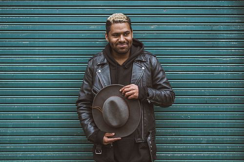 man holding black cowboy hat standing in front of roll-up door