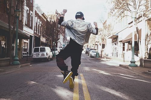 man jumping on the middle of the street during daytime