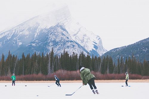 people playing hockey on icefield at datyime