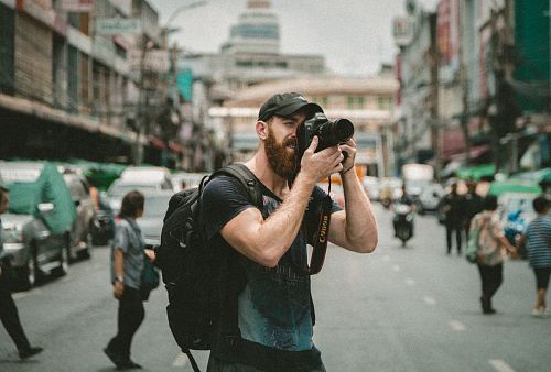 shallow focus photography of man using a DSLR camera