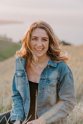 smiling woman sitting on grass during daytime