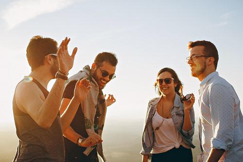 three men and one woman laughing during daytime