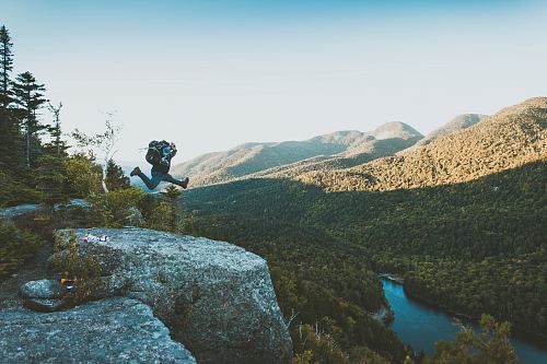 time lapse photo of person jumping from cliff within mountain range