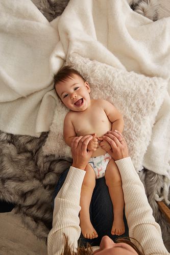 toddler smiling while lying on white pillow