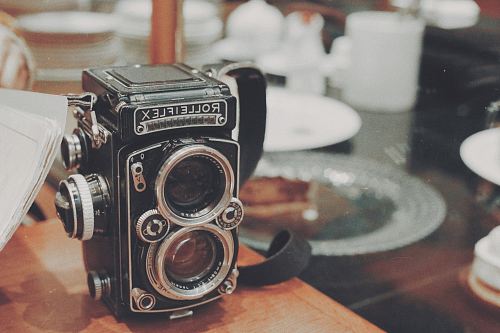 vintage black and gray Rolleiflex camera on wooden desk
