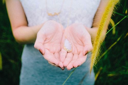 white and gold-colored pendant on person's hand